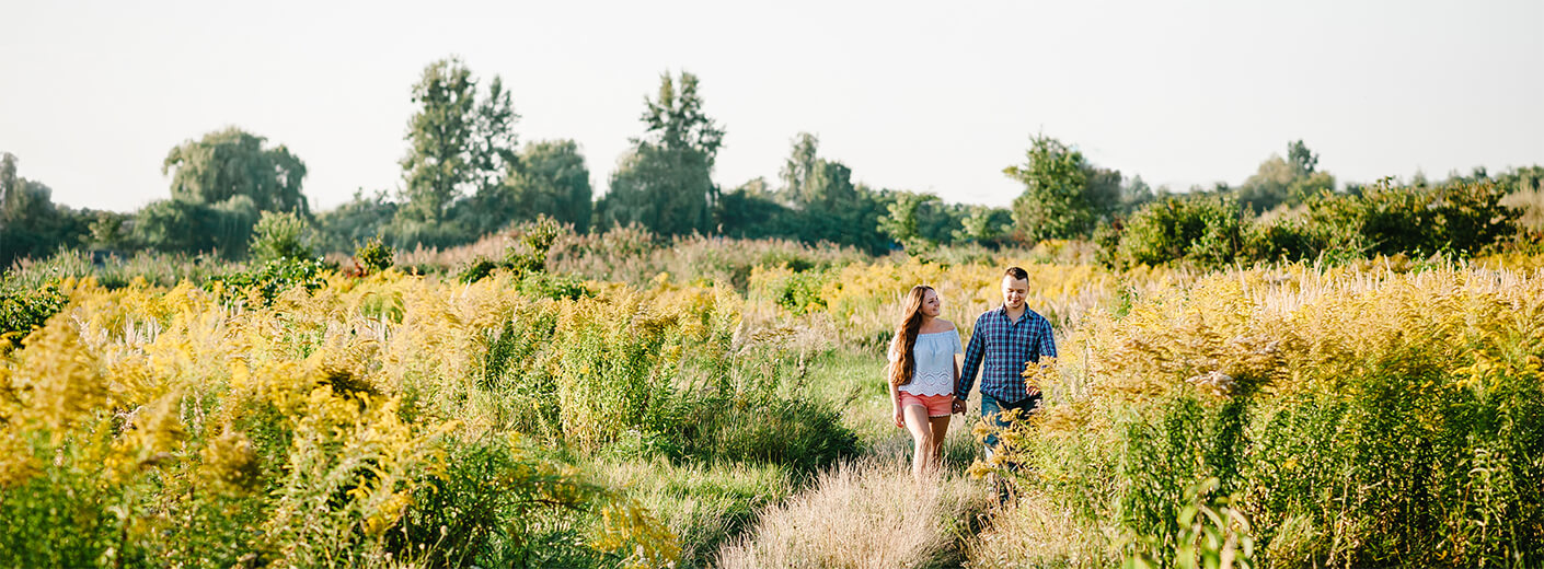 Couple holding hands and walking through grassy area